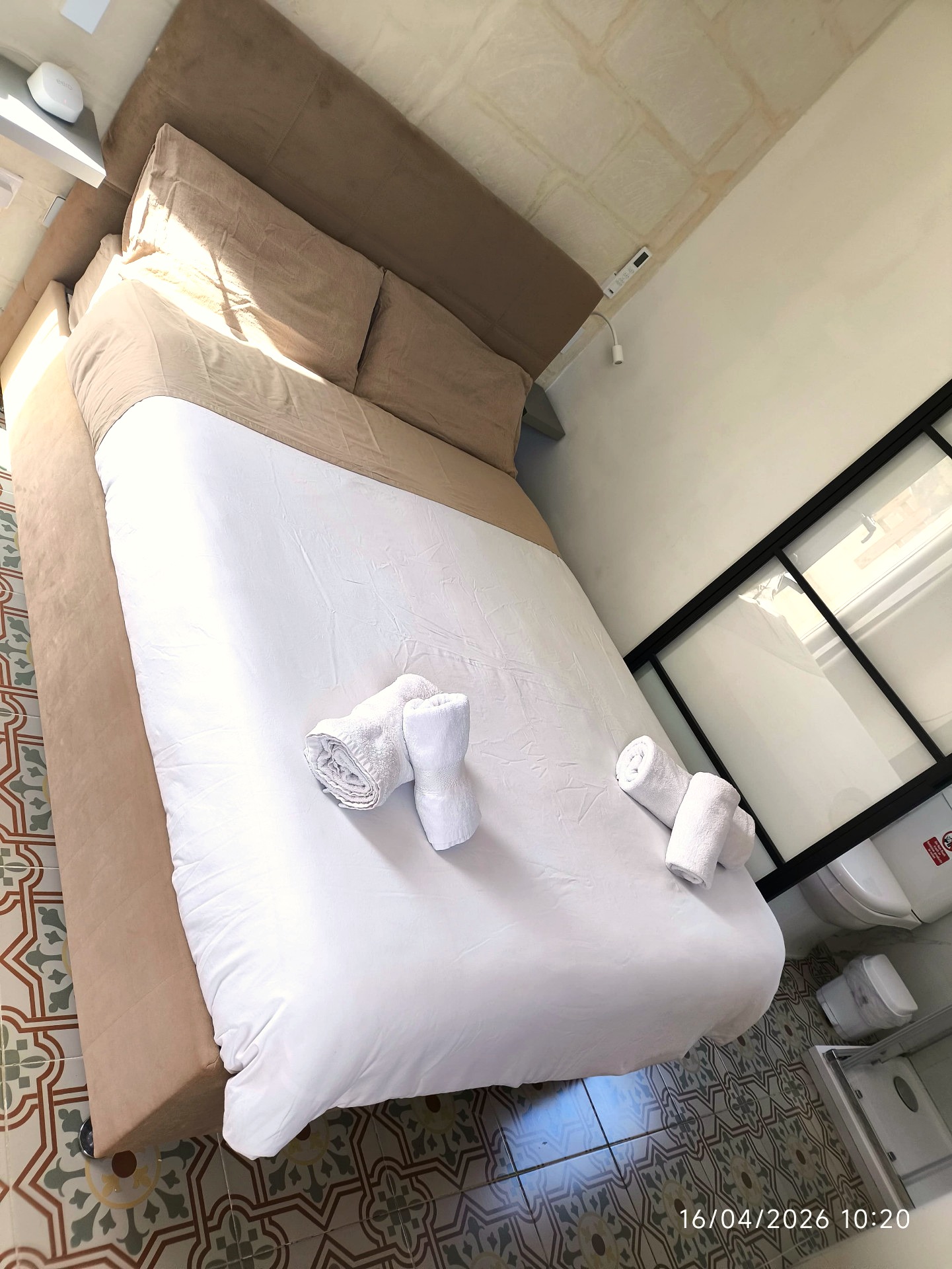 Bright bedroom with crisp white linens and patterned Maltese floor tiles