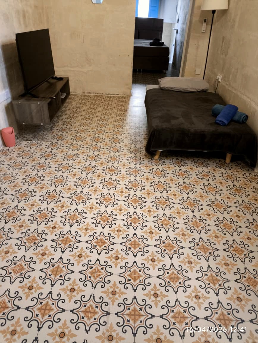 Spacious living and sleeping area with traditional tiled flooring and stone walls