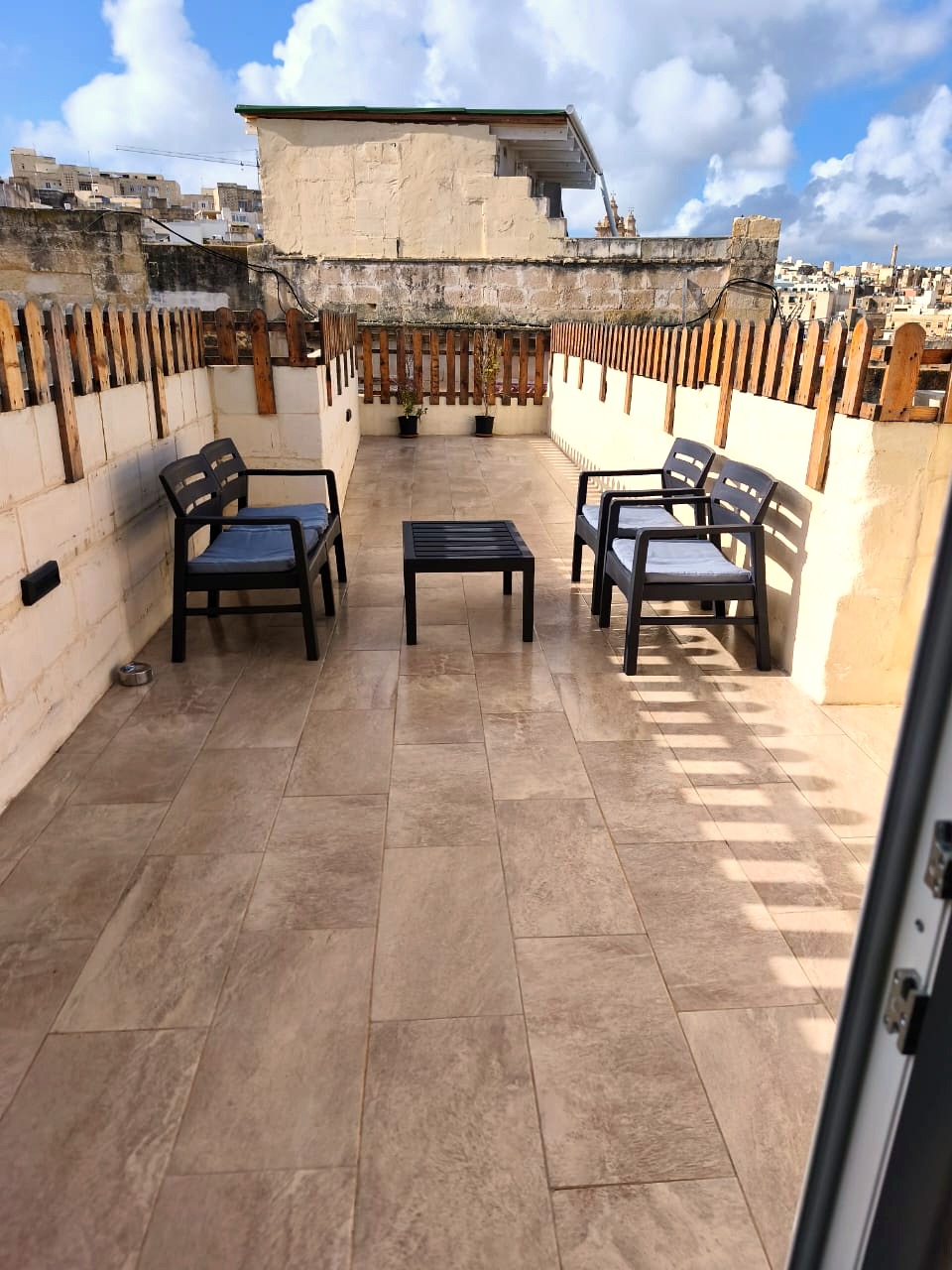 Sunlit rooftop terrace with seating and skyline views in Cospicua